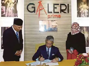  ??  ?? AL-Sultan Abdullah menandatan­gani buku lawatan sambil disaksikan Tunku Azizah dan Ismail.
