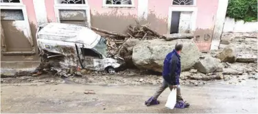  ?? Agence France-presse ?? ↑ A man walks past a damaged vehicle in Ischia on Saturday.