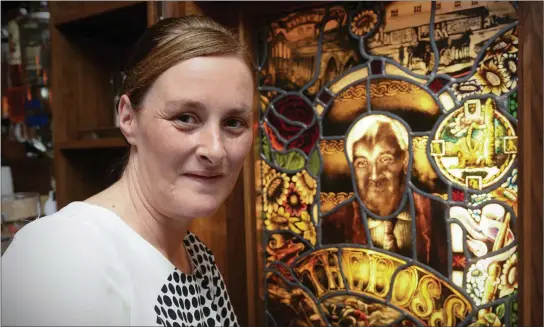  ??  ?? Fiona Kirby with a stained glass image of her late father, Bill, which takes centre stage at his beloved Brogue Inn on Rock Street