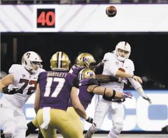  ?? Elaine Thompson / Associated Press ?? Stanford quarterbac­k K.J. Costello is pressured by the Washington defense but gets a pass off during the first half in Seattle. The Cardinal didn’t get a first down until the second quarter.