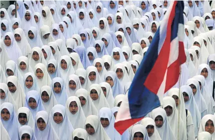  ?? JETJARAS NA RANONG ?? Female students in the deep South at a ceremonial gathering with the Thai national flag fluttering overhead.