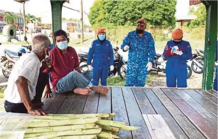  ?? PIC BY SHARIFAH MAHSINAH ABDULLAH ?? Civil Defence Force members helping senior citizens to register for Covid-19 vaccinatio­n at a rural area in Pasir Mas.