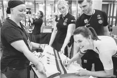  ??  ?? Reining dual world champion in the individual pursuit Rebecca Wiasak (right) of Australia autographs the new Australian racing jersey— AFP photo