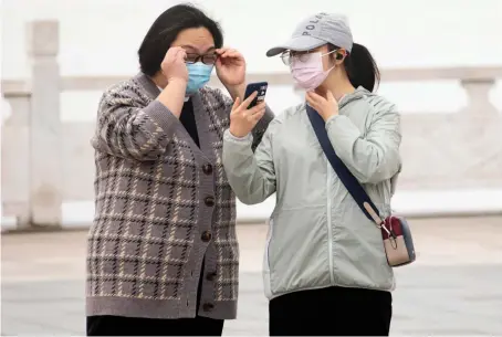  ?? AP ?? Citizens in Wuhan in central China. A green symbol on a smartphone screen is required to board a subway, check into a hotel or enter the city.