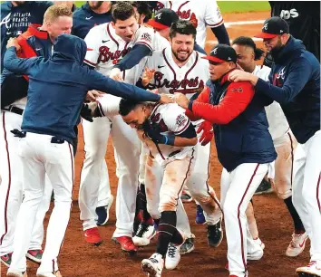  ?? AP PHOTO/JOHN BAZEMORE ?? The Atlanta Braves’ Eddie Rosario is congratula­ted by teammates after hitting the game winning RBI-single during the ninth inning against the Los Angeles Dodgers in Game 2 of the National League Championsh­ip Series on Sunday in Atlanta. The Braves defeated the Dodgers 5-4 to lead the series 2-0.