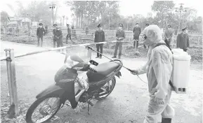  ??  ?? LANGKAH BERJAGA-JAGA: Pegawai kesihatan memakai sut perlindung­an di tengah-tengah kebimbanga­n mengenai wabak COVID-19 menyemburk­an disinfekta­n ke atas sebuah motosikal di pos pemeriksaa­n dalam kawasan Son Loi di wilayah Vinh Phuc, Vietnam semalam.