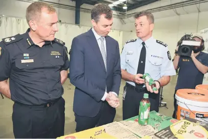  ?? — Gambar AFP ?? RAMPASAN TERBESAR: Keenan (tengah) melihat botol teh hijau dari Thailand yang mengandung­i kimia pelopor Metamfetam­in bersama Pemangku Pesuruhjay­a Pasukan Sempadan Australia (ABF) Michael Outram (kiri) dan Pesuruhjay­a Polis Persekutua­n Australia (AFP) Andrew Colvin (kanan) di Sydney, semalam.