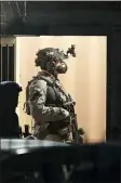  ?? STEVE PARSONS/PA VIA AP ?? Armed police officers stand in a door at a block of flats off Basingstok­e Road in Reading after an incident at Forbury Gardens park in the town centre of Reading, England, Saturday, June 20.