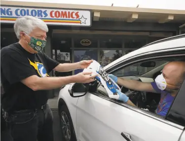  ?? Photos by Ben Margot / Associated Press ?? Joe Field, owner of Flying Color Comics in Concord, makes a curbside delivery of comic books to Elias Panos. Free Comic Book Day, which Field created, would have been Saturday. But not this year.