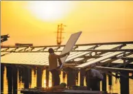  ?? FU JIANBIN / FOR CHINA DAILY ?? Workers install solar panels at a photovolta­ic power station in Changxian county, Jiangxi province, in April. The area below the panels also serves as a fish farm, increasing the efficient use of space and generating more income.