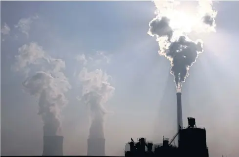  ?? REUTERS ?? A coal-burning power plant can be seen behind a factory in China. Putting a price on carbon would be an effective way to avoid the building of new coal power plants.