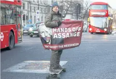  ?? REUTERS ?? A man rides a skateboard holding a banner with an image of WikiLeaks founder Julian Assange in London on Wednesday.