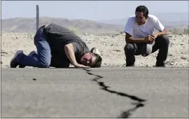  ?? MARCIO JOSE SANCHEZ — THE ASSOCIATED PRESS ?? Ron Mikulaco, left, lowers his head to get a look at a crack caused by an earthquake next to his nephew Brad Fernandez on Highway 178on Saturday outside Ridgecrest.