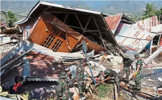  ??  ?? Not giving up: Rescue personnel searching for survivors at a collapsed home in Balaroa, West Palu. — AFP