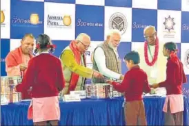  ?? ANI ?? Prime Minister Narendra Modi along with governor Ram Naik and chief minister Yogi Adityanath serving food to underprivi­leged children during a programme organised to mark the serving of the 3rd billionth meal by the Akshaya Patra Foundation, in Vrindavan on Monday.