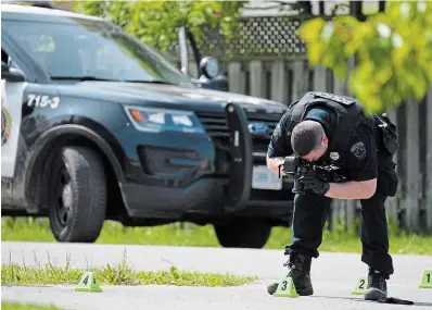  ?? THE HAMILTON SPECTATOR ?? A Hamilton police forensics officer photograph­s evidence across the street from where two people were shot dead Saturday.