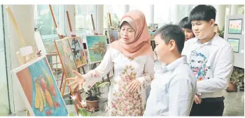  ?? — Photo by Tammy Chong ?? Fatimah, accompanie­d by the children during her tour at the exhibition, takes a closer look at an artwork.