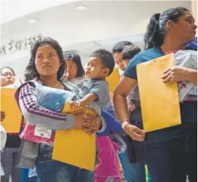  ?? Loren Elliott, AFP ?? Immigrants wait to head to a nearby Catholic Charities relief center after being dropped off at a bus station shortly after release from detention through the “catch and release” immigratio­n policy on June 17 in Mcallen, Texas.