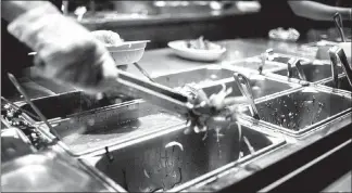  ?? JOHN TAGGART / THE NEW YORK TIMES ?? Servers prepare a dish at Chipotle in New York.