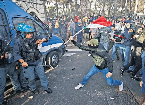  ?? ?? Masked protesters brandishin­g Italian flags clash with riot police in Rome during a demonstrat­ion against the ‘green pass’, a Covid vaccine passport all Italian workers must carry from Friday