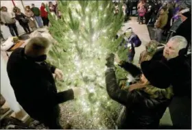  ?? NEWS-HERALD FILE ?? With the help of Behm Family Funeral Homes’ staff, visitors to the last Candleligh­t Service of Remembranc­e place ornaments bearing loved ones’ names on the tree outside the Behm location in Madison Village in this 2016 photo.