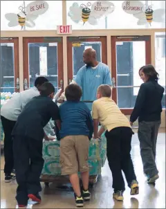  ??  ?? Students on Oct. 8 help unload bottled water donated to their Flint elementary school because of the lead crisis.