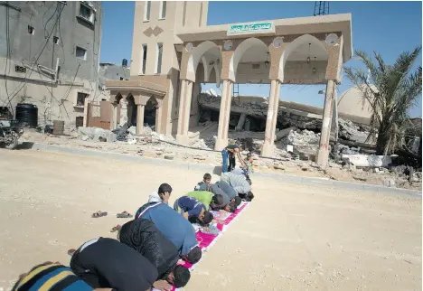  ?? KHALIL HAMRA/THE ASSOCIATED PRESS ?? Palestinia­ns attend the Friday noon prayers next to the rubble of a destroyed mosque in Khan Younis, southern Gaza Strip.