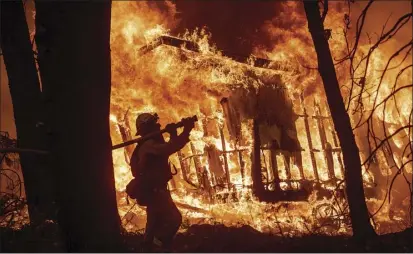  ?? AP photo ?? Firefighte­r Jose Corona sprays water as flames from the Camp Fire consume a home in Magalia, Calif., north of Paradise, on Friday.