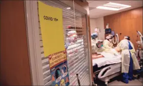  ?? John Moore / Getty Images ?? A prone team wearing personal protective equipment prepares to turn a COVID-19 patient onto his stomach in a Stamford Hospital intensive care unit on April 24, 2020.