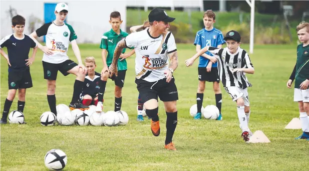  ??  ?? KICKING ON: Luke Wilkshire runs a drill with Caravella academy player Toby Webster. Picture: BRENDAN RADKE