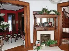  ??  ?? Pocket doors open off the foyer into the formal living room which has roping detailed ceiling carvings and ornate wall frames. Wood trim accents the turret seating nook and in-laid carpeting is set within the woven wood flooring. A decorative fireplace has a double mantel and wrought-iron cover.