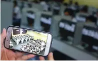  ?? DIPTA WAHYU/JAWA POS ?? PRAKTIS: Sejumlah guru SMKN 3 Surabaya menggunaka­n sistem pengawasan melalui aplikasi di telepon genggam untuk memantau UNBK kemarin.