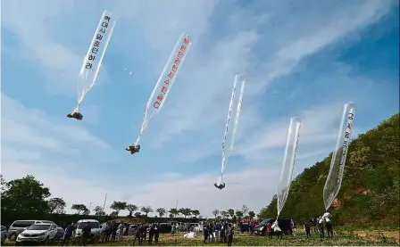  ??  ?? Spreading the word: South Korean and US activists releasing balloons carrying anti-Pyongyang leaflets at a field near the demilitari­sed zone at the border city of Paju.