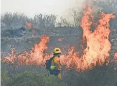  ?? ROBERT HANASHIRO/USA TODAY ?? A firefighte­r keeps a watchful eye on flames in Thousand Oaks, Calif., this month.