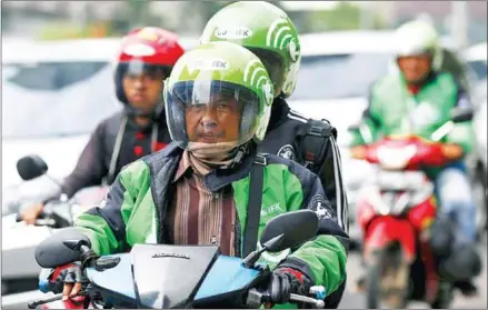  ??  ?? A driver and passenger ride on a motorbike, part of the Go-Jek ride-hailing service, on a busy street in central Jakarta, Indonesia on December 18, 2015.