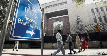  ??  ?? Juggling act: People walking past the RBI building in New Delhi. The RBI faces a juggling act over whether to bolster growth or retain its prime target of keeping inflation checked at 4% in the medium term. — Reuters