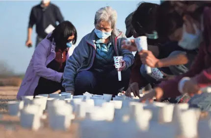  ??  ?? Lifang Huang, center, lights candles as hundreds gather at Shelby Farms Park on Sunday to protest violence against Asians in reaction to a recent mass shooting in Georgia that left eight people dead.