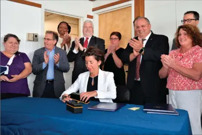  ?? Submitted photo ?? At a ceremonial bill signing held at The Providence Center on Monday, Gov. Gina Raimondo signs several bills into law that deal with the opioid crisis. From the left, Sen. Elizabeth A. Crowley, Sen. Joshua Miller, and from the right, Rep. Mia A....