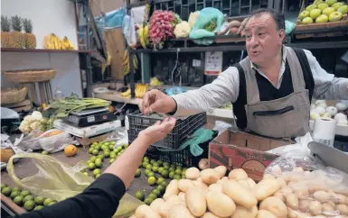  ?? FERNANDO LLANO/AP ?? A shopkeeper makes change for a customer last week in the Mercado de Medellin in Mexico City. Across the Latin American region, residents are seeing inflation raise the cost of basic goods and everyday necessitie­s to sometimes prohibitiv­e levels.