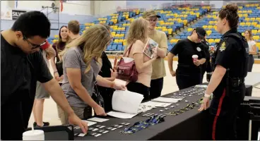  ?? HERALD PHOTO BY JUSTIN SIBBET ?? Lethbridge Police Service Const. Allison Williams talks with Carson Pennington during a recruiting event Friday at the Lethbridge College gymnasium.