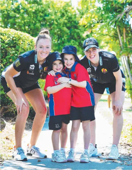  ?? Picture: ZAK SIMMONDS ?? GOOD CAUSE: Townsville Fire players Ally Malott and Tess Madgen took part in the Peter Project walk to raise awareness around mental health with students from The Cathedral School Elliette Young, 6, and Adeline Young, 8.