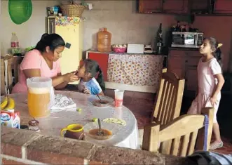  ?? Photograph­s by Katie Falkenberg Los Angeles Times ?? ROSA ICELA NAVA sits down to lunch with her daughters, Michelle, center, and Abril. Nava was pregnant with Abril when her husband made his first trip to the United States to find work.