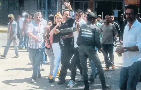  ?? JUAN NEIRA / EFE ?? Agentes de la Guardia Nacional Bolivarian­a impiden a Luisa Ortega, en el centro, con pantalones blancos, entrar en la sede de la Fiscalía
