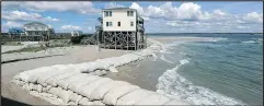  ?? — CHUCK BURTON/AP ?? Stewart Thomason places sandbags and a tarp to prevent flooding at his home on the Isle of Palms, S.C., yesterday. Below, Hurricane Florence swirls far below the Internatio­nal Space Station. Above, sandbags surround homes on North Topsail Beach, N.C.