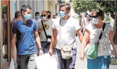  ?? // ROCÍO RUZ ?? Tres sevillanos, con bolsas de compras, paseando por el Centro de Sevilla protegidos con mascarilla­s