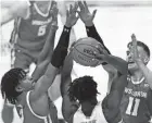  ?? NIKOS FRAZIER / INDYSTAR ?? UW's Aleem Ford, left, and Micah Potter harass North Carolina forward Day'Ron Sharpe during the first half Friday night.