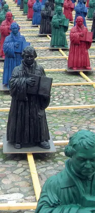  ??  ?? Popolare Sopra «Herr Martin», dipinto digitale di Dorothee Golz, 2015, a destra installazi­one di Ottmar Hörl nella piazza del mercato a Wittenberg, 2010 e in alto la gigantogra­fia di Lutero sui tram di Halle