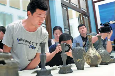  ?? DU YANG / CHINA NEWS SERVICE ?? He Junqing, whose father, He Gang, donated ancient relics to the Palace Museum in Beijing, takes a look on Thursday at some of the Yuan Dynasty (1271-1368) artifacts his father found while digging in his yard.