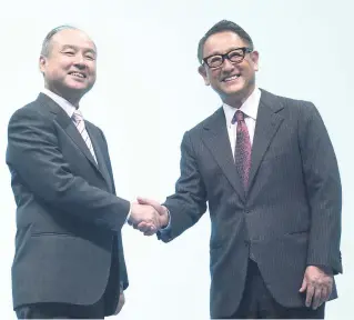  ?? AP ?? SoftBank Group Corp Chairman Masayoshi Son (left) and Akio Toyoda, president of Toyota Motor Corporatio­n shake hands during a press conference in Tokyo on Thursday, October 4.