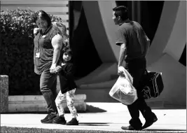  ?? ASSOCIATED PRESS ?? IN THIS JULY 26 FILE PHOTO, A CHILD HOLDS THE HAND of a Lutheran Social Services worker as she looks back to a man as they arrive at Lutheran Social Services in Phoenix. The Trump administra­tion and the American Civil Liberties Union are proposing...